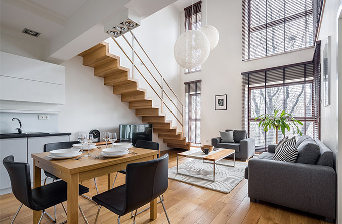 modern living space with wooden stairs dining table and seating area featuring three light fixtures and large windows